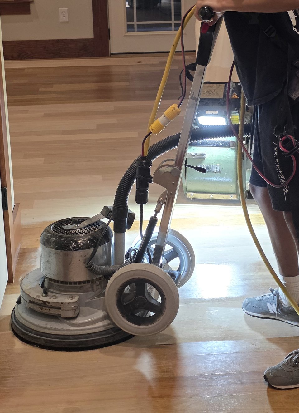 A craftsman operating a floor sanding machine in a hallway