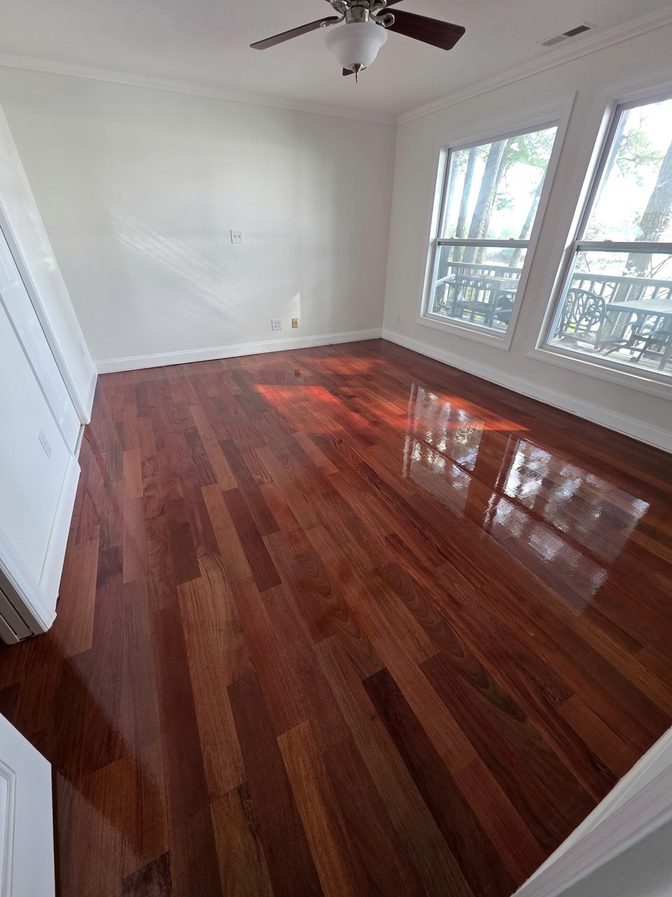 Reddish wood floor in a room with a ceiling fan