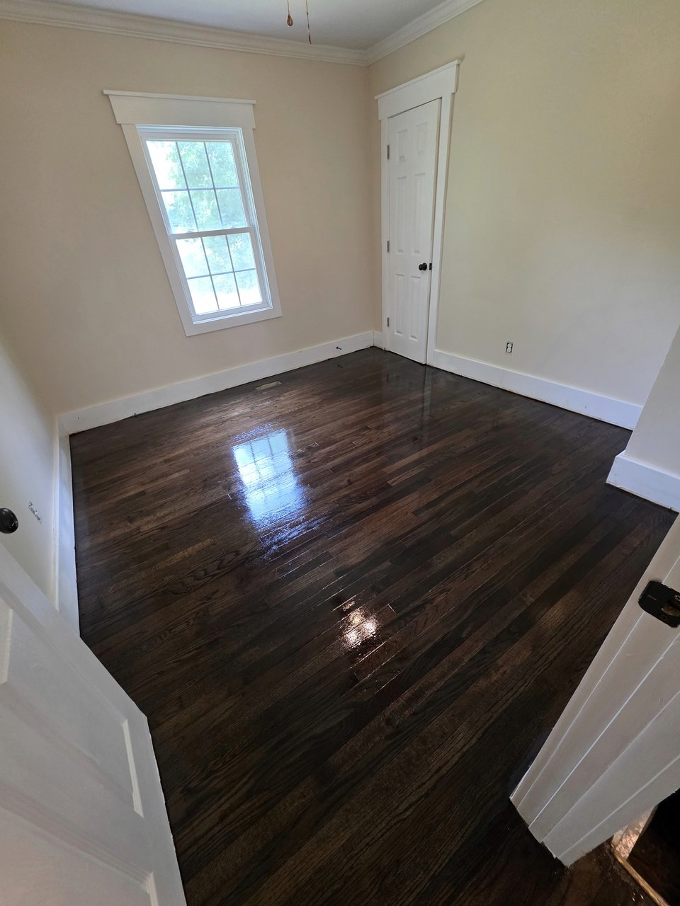 Dark wood floor beneath a bedroom window