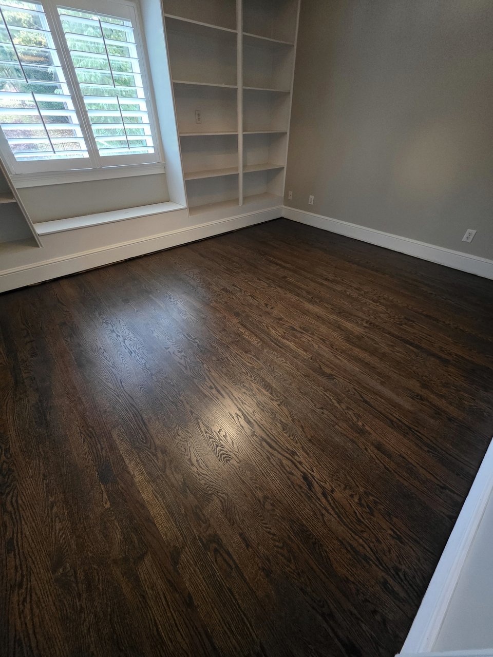 Dark stained floor beside shuttered windows